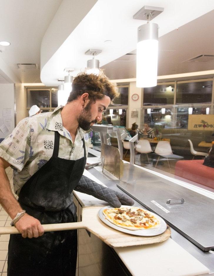 A Pitzer student shuffles a pizza off a pizza peel at the Shakedown Cafe